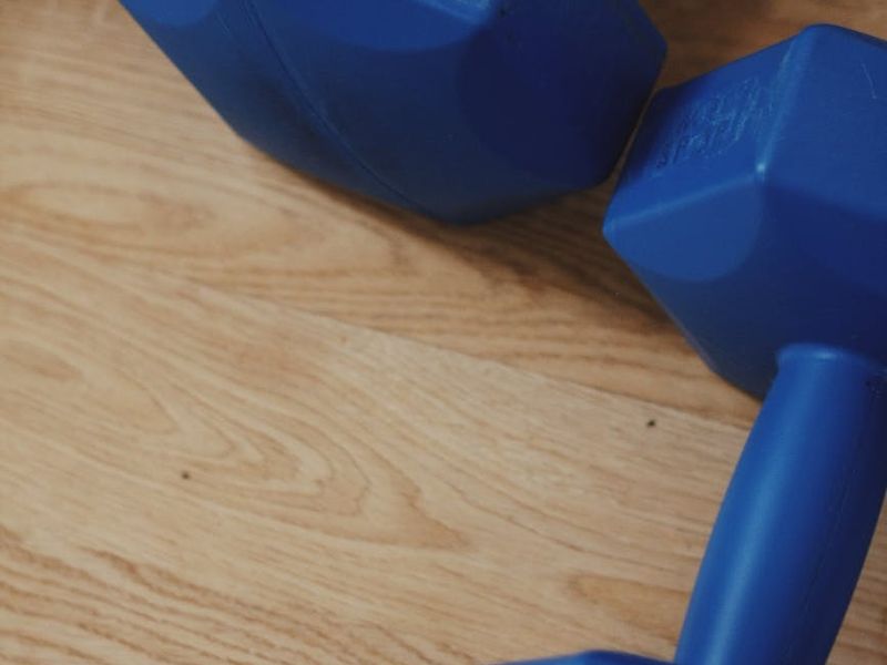 Detailed shot of a chrome dumbbell on a wooden floor.